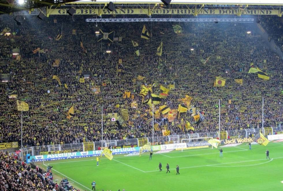 Ausverkauftes Bundesliga-Stadion mit gelber Fankurve und Fahnen